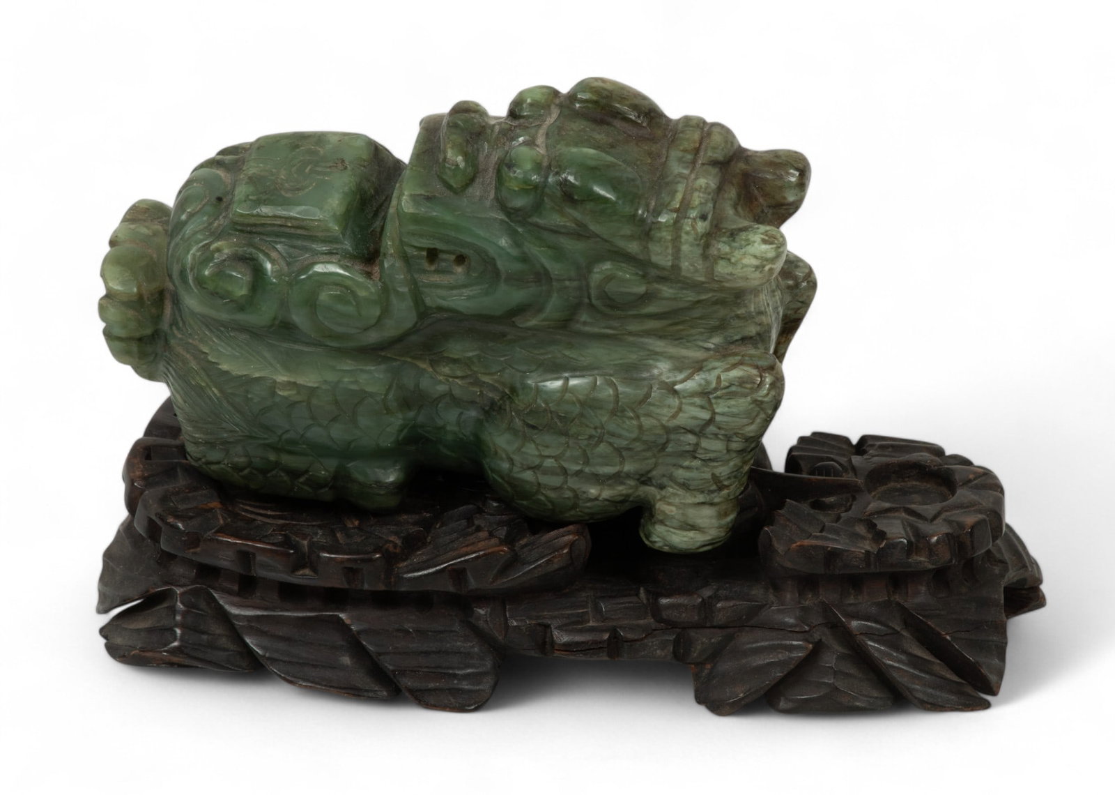 Chinese Green Jade Foo Dragon Ca. 1900, H 4.3" W 2" L 6.5": Chinese Green Jade Foo Dragon Ca. 1900, H 4.3" W 2" L 6.5" | Foo dragon with scales, head turned backwards. Bulging eyes. Prominent teeth. No wood stand. Provenance: Property of a Prominent Grosse Poi