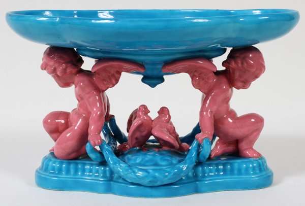 MINTONS MAJOLICA FIGURAL CENTERPIECE, 1873, H 6",: MINTONS MAJOLICA FIGURAL CENTERPIECE, 1873, H 6", W 10":A quatrefoil bowl raised on two cherub-form supports centered by doves, glazed turquoise blue and coral pink. Impressed "Mintons" with date ciph