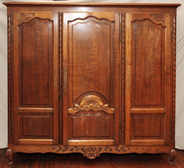 BELGIAN CARVED OAK WARDROBE, 20TH CENTURY, 76"H: BELGIAN CARVED OAK WARDROBE, 20TH CENTURY, H 76", W 74", D 24":Beveled cornice above three paneled doors with floral and shell carvings, on whorl feet with acanthus carved knees. Two doors open to han