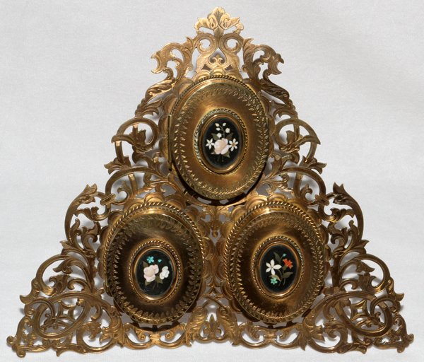 HOWELL, JAMES & CO., ENGLISH BRASS FRAME, H 9": HOWELL, JAMES & CO., ENGLISH BRASS & PIETRA DURA TRIPLE FRAME, LATE 19TH C., H 9":Triangular shape with pierced scroll motif overall, fitted with three oval doors, each centered by a pietra dura flora