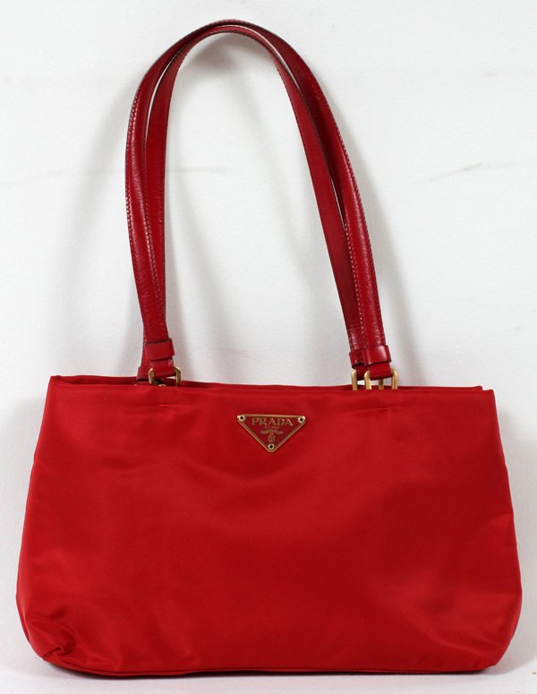 PRADA RED NYLON HAND BAG, W 10": PRADA RED NYLON HAND BAG, W 10":With red leather handles and trim, two magnetic snap closures and two zippered pockets at the interior, lined in black "Prada" fabric, labeled "Prada, Made in Italy". M