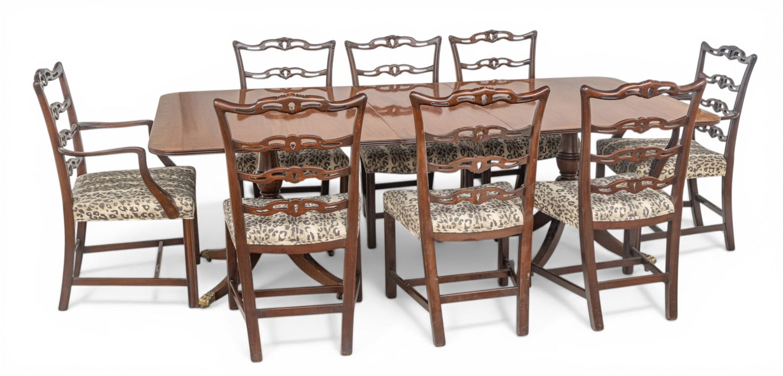 Carved Mahogany and Printed Leopard Uholstery Dining Chairs (8) and Table 9 PCS: Carved Mahogany and Printed Leopard Uholstery Dining Chairs (8) and Table 9 PCS A banded dining table raised on double pedestal bases with carved down swept legs ending in brass paw feet with castors.