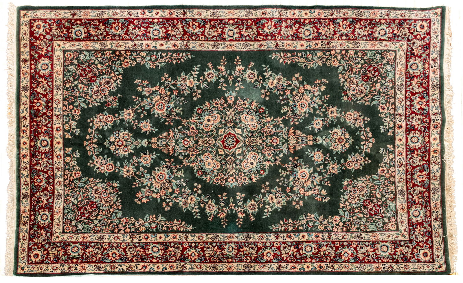 Persian Kerman Handwoven Wool Rug, Ca. 1970, W 6' L 9': Persian Kerman Handwoven Wool Rug, Ca. 1970, W 6' L 9' Deep green field with center medallion in close field. Intricate garland motif. Provenance: Property from the collection of Margarat Weerakoon,
