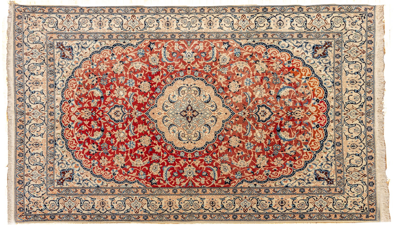 Indo-Nain Design Handwoven Wool Rug, Ca. 1980, W 6' 6" L 10': Indo-Nain Design Handwoven Wool Rug, Ca. 1980, W 6' 6" L 10' Red field bracketed in ivory. Overall scrolling vine and floral designs in navy and ivory. Small touches of silk highlights. Provenan