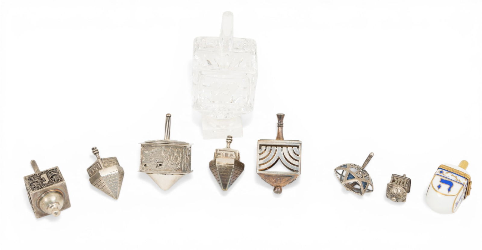 Judaica, Dreidels: 5 Sterling, 1 Christofle, 1 Glass, 1 Porcelain 9 PCS: Judaica, Dreidels: 5 Sterling, 1 Christofle, 1 Glass, 1 Porcelain 9 PCS Five sterling dreidels made in Israel all marked 925 weigh 5.3Toz. One dreidel in silver plate by Christophe. One unmarked silve