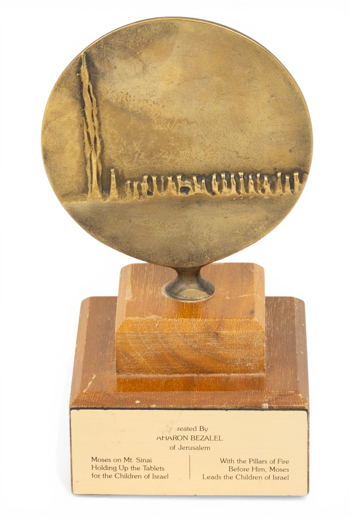 Aharon Bezalel, (Jerusalem) Judaica Bronze Circular Sculpture, Moses H 5" Dia. 4.5" 1 PC: Aharon Bezalel, (Jerusalem) Judaica Bronze Circular Sculpture, Moses H 5" Dia. 4.5" 1 PC Scene of Moses on Mt Sinai holding up the tablets. Verso depicts Moses leading the children of Israel. Mounted