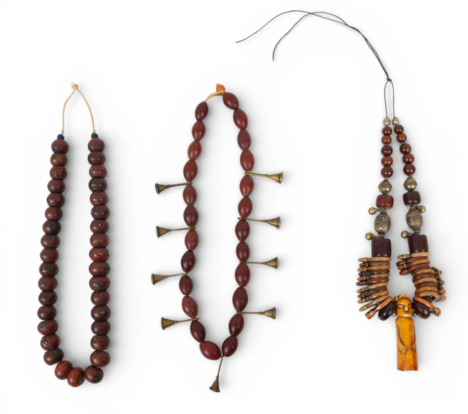 Dark Red-Brown Beaded Necklaces, One with Carved Figure Pendant 3 PCS: Dark Red-Brown Beaded Necklaces, One with Carved Figure Pendant 3 PCS Three beaded necklaces, one having brass beads and one with carved figure pendant. Provenance: Property from a Midland, MI