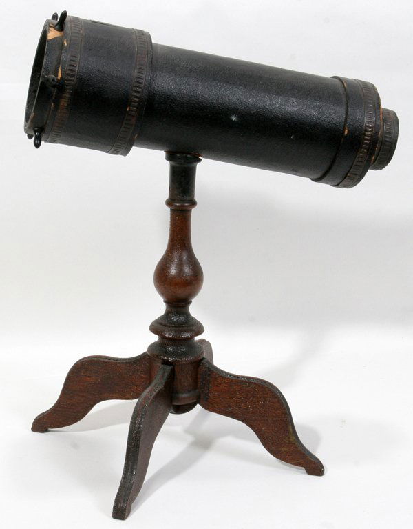 CHARLES G. BUSH KALEIDOSCOPE, H 13 1/2", L 11": CHARLES G. BUSH (AMERICAN 1825-1900), KALEIDOSCOPE, H 13 1/2", L 11":Black hardboard with a spoked wheel rotating an object cell, mounted atop a four-legged wooden stand. Patent date marked on the sta