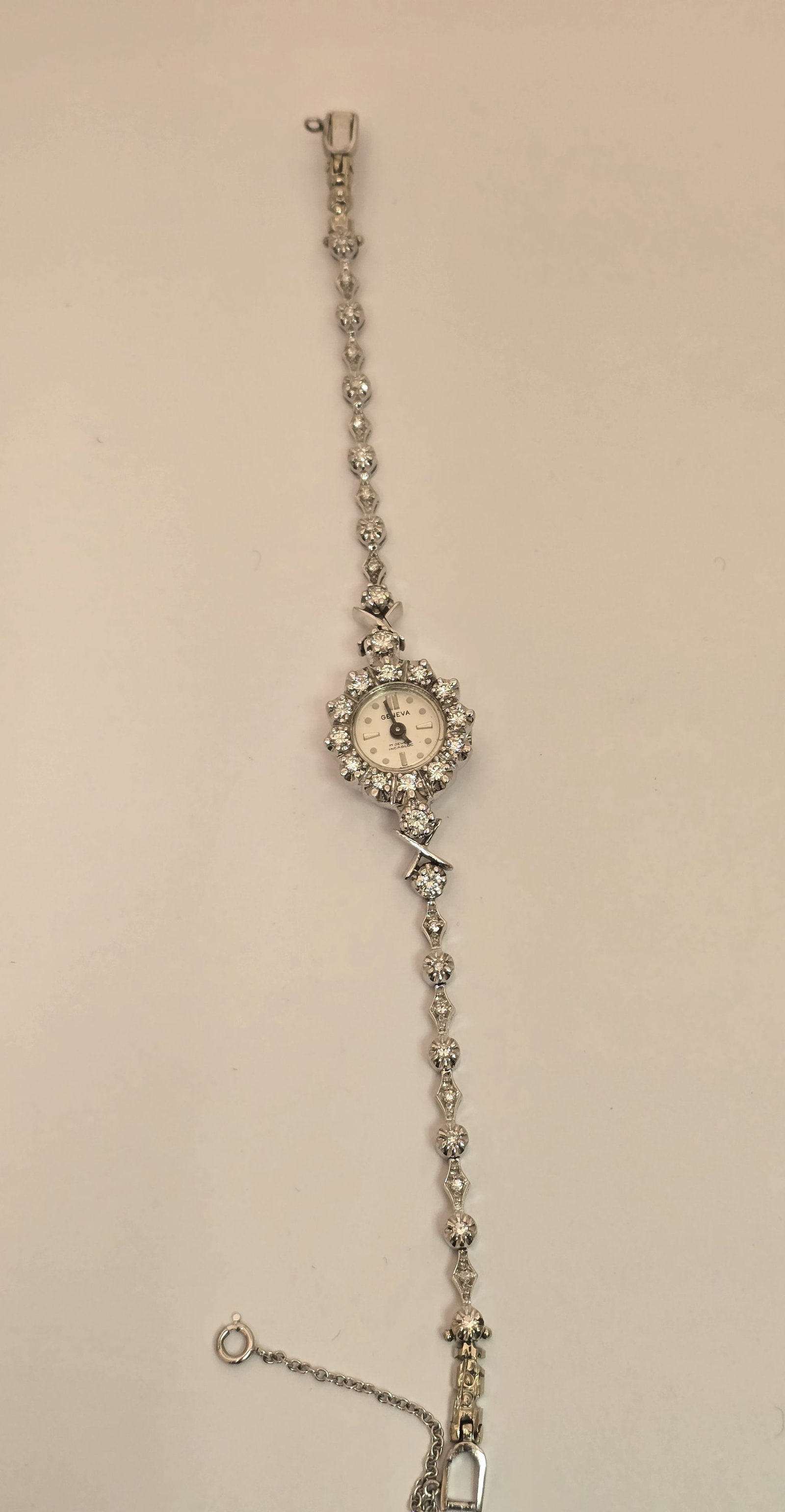 Geneve Ladies' 14K White Gold and Diamond Cocktail Watch L 7" 17 g: Geneve Ladies' 14K White Gold and Diamond Cocktail Watch L 7" 17 g A ladies' 14k white gold and diamond bezel cocktail watch having a folding clasp and safety chain. Marked 14k 181 to the back of the