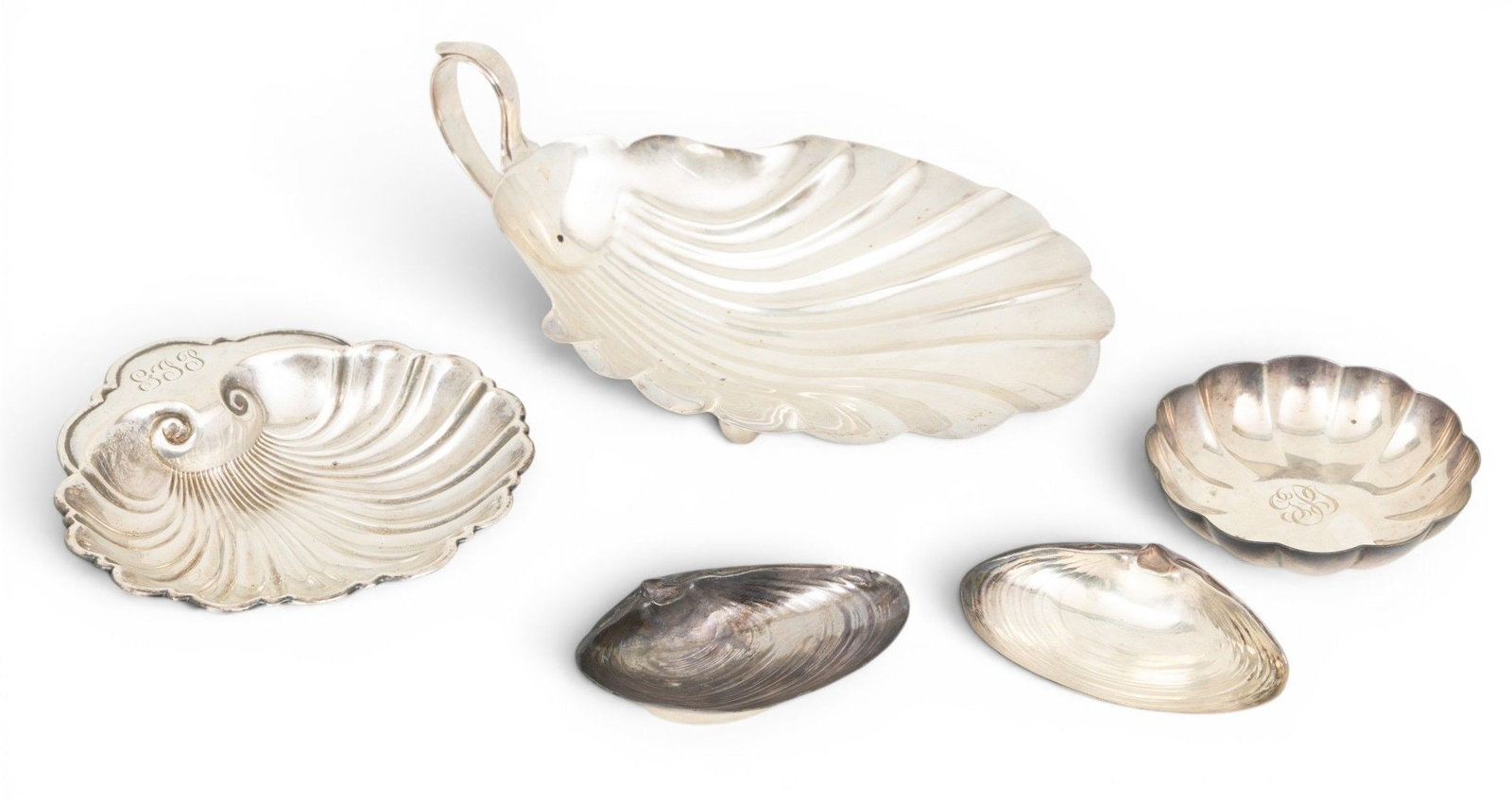 Sterling Silver Shell Form Dishes 5 PCS: Sterling Silver Shell Form Dishes 5 PCS (1.) A sterling silver shell-form bon bon dish with a handle, resting on two ball feet. Unidentified maker. Marked Sterling / 55. (2.) A Gorham shell-form dish.