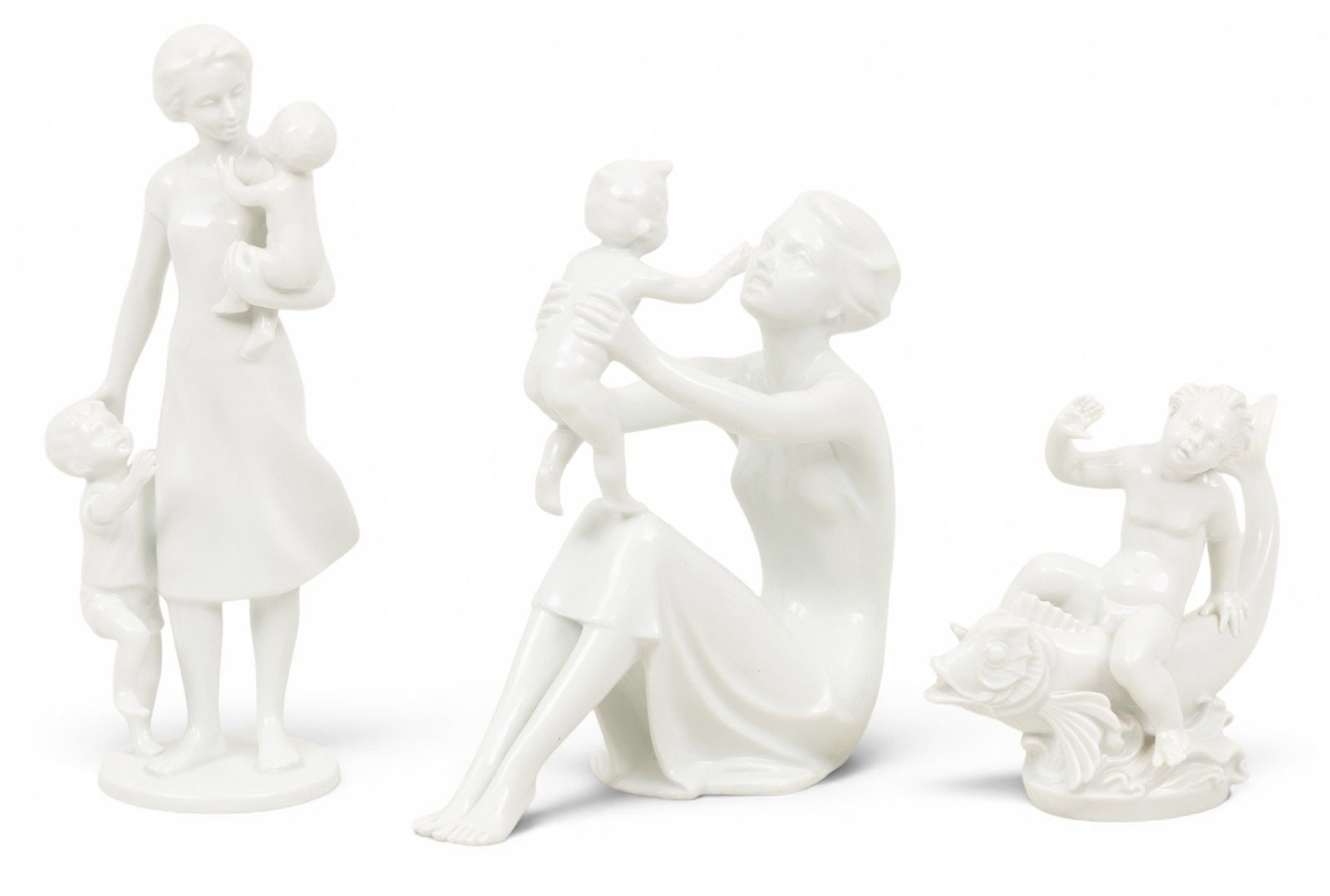 AK (West Germany) Porcelain Figures: Cherub, Mother and Child 1958, H 10" 3 PCS: AK (West Germany) Porcelain Figures: Cherub, Mother and Child 1958, H 10" 3 PCS Cherub with dolphin H 5.5". Mother and child figures 8" and 10". Provenance: Property of a Bloomfield Hills, MI pr