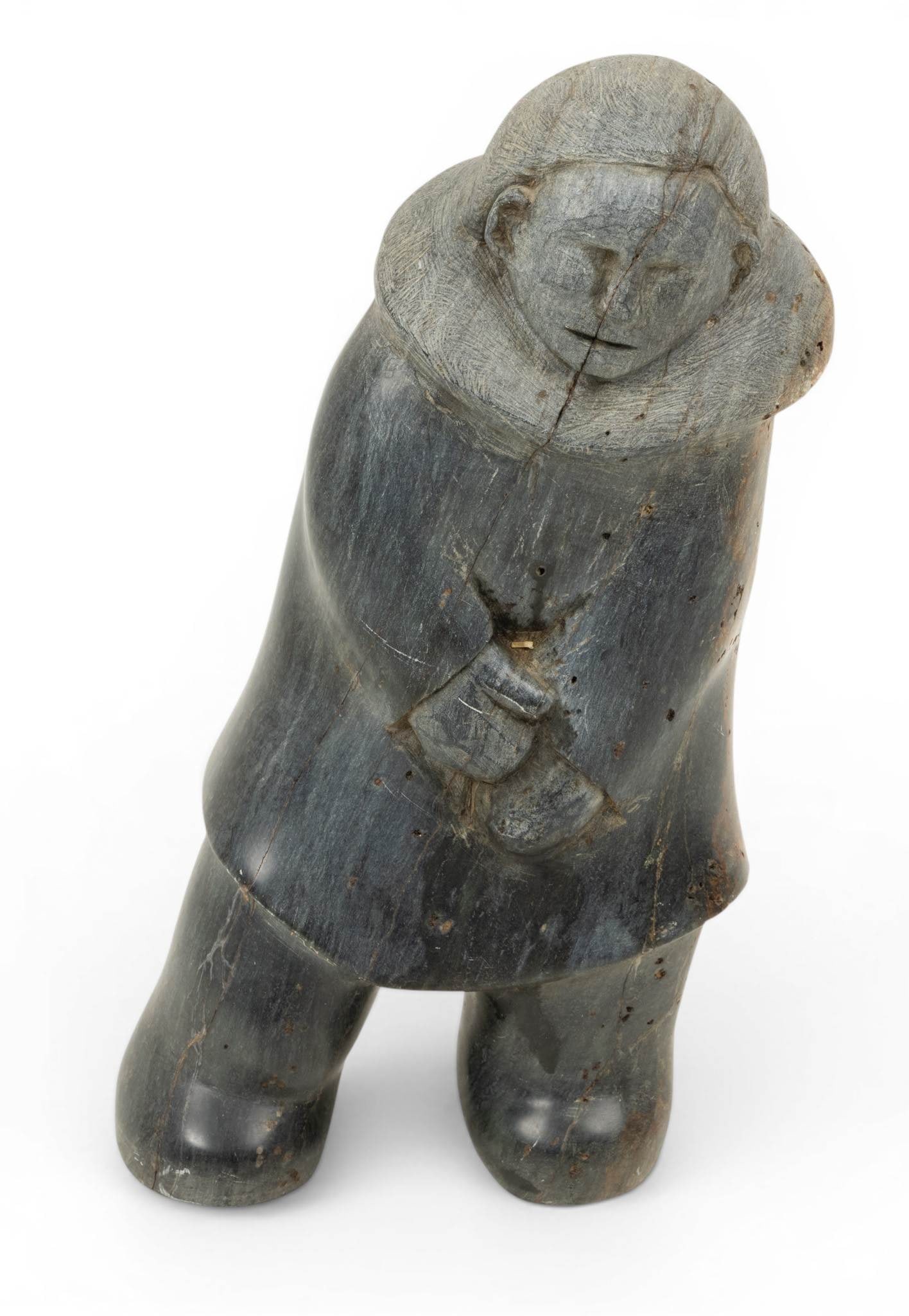 Ric Seeganna (American/Inupiaq Culture, B. 1949) Carved Stone Sculpture 1977, H 11.5" W 5": Ric Seeganna (American/Inupiaq Culture, B. 1949) Carved Stone Sculpture 1977, H 11.5" W 5" Signed and dated 77 on parka underside. Depicting a leaning male figure dressed in a parka (qulittaq) with ru