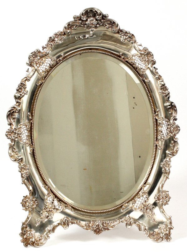 AMERICAN STERLING EASEL MIRROR: AMERICAN STERLING EASEL MIRROR, H 22", W 16": Having an overall scroll and leaf design with a beveled oval mirror. Marked on the underside "Sterling 123 F" (see additional photo). APPROX 90 TROY OZ (I