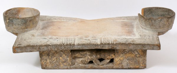 AFRICAN DIVINATION BOARD: AFRICAN DIVINATION BOARD, H 6" W 9 1/2" L 19":Probably from the Yoruba tribe. Rectangular form with two cups at each end, geometric designs in bas-relief along the edges. Raised on a figural pedestal 