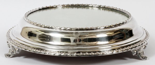 ENGLISH SILVERPLATE MIRRORED PLATEAU GOLDSMITH'S: ENGLISH SILVERPLATE MIRRORED PLATEAU, GOLDSMITH'S CO., LONDON, H 4", DIA 16":A round electroplate silver frame raised on three scroll feet, etched in two places with a hand clenching a laurel wreath; 