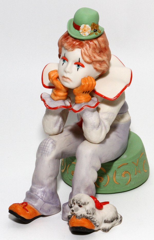 CYBIS BISQUE FIGURE OF A SEATED CLOWN: CYBIS BISQUE FIGURE OF A SEATED CLOWN, H 6 1/2":A boy dressed as a clown, seated, with a dog at his feet, signed.