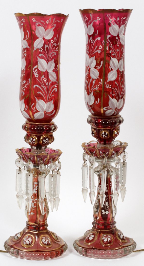 FRENCH CRANBERRY GLASS LAMPS PAIR: FRENCH, CRANBERRY GLASS LAMPS, PAIR, H 22":Electrified. Fired gold and hand painted white flower motif, fired gold highlights, faceted hanging prisms, clear bead motif on edge of base.
