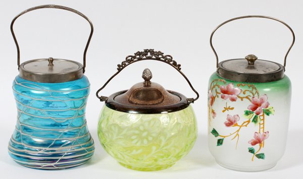 ART GLASS BISCUIT JARS THREE: ART GLASS BISCUIT JARS, THREE, H 6 1/2"-7 1/2":Includes a Loetz style glass biscuit jar in a rounded, baluster form, having a blue iridescent sheen with applied white thread decoration, mounted with a
