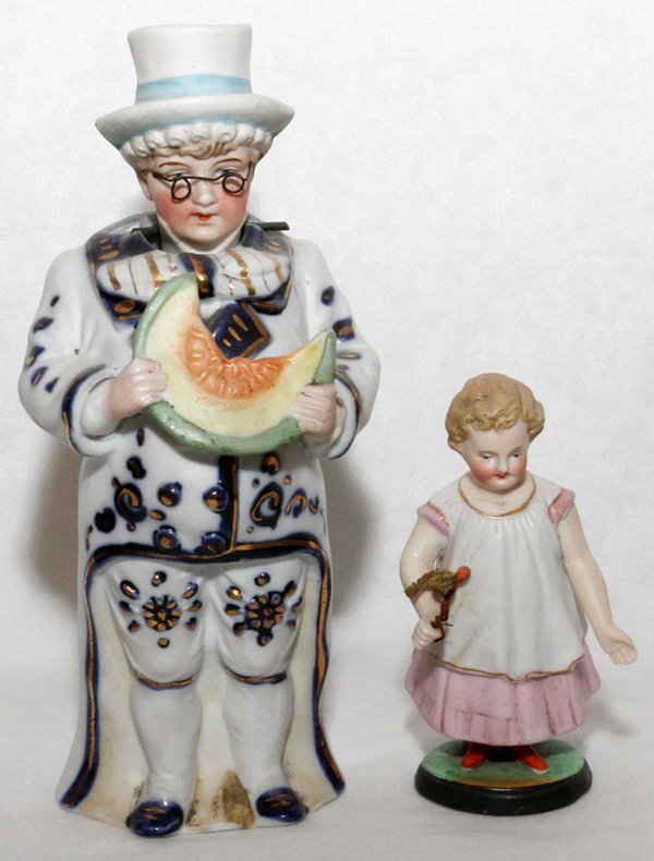 GERMAN BISQUE NODDER FIGURES C. 1890 TWO: GERMAN BISQUE NODDER FIGURES, C. 1890, TWO, H 8" & 4 1/4":Two figures: man with wire rim glasses and top hat holding watermelon, head bobs. Child figure swivels on separate base "legs", blue anchor ma