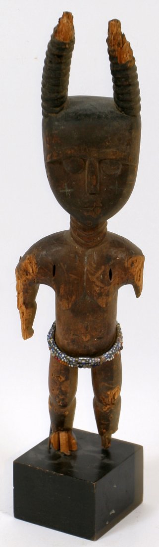 CARVED AFRICAN TRIBAL STANDING FIGURE W/ HORNS: CARVED AFRICAN TRIBAL STANDING FIGURE WITH HORNS, H 13":Having carved human features to the face below two twisted horns. Multicolor bead hoops ornamenting the waist. No stand.