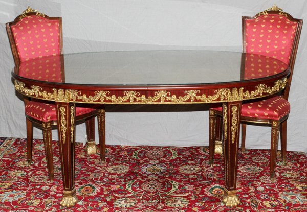 FRENCH STYLE OVAL DINING TABLE: FRENCH STYLE OVAL DINING TABLE, H 31.5", L 72", D 44":Having ormolu flower and vine design at the apron, paw feet and a glass top. The two chairs have ormolu enhancements with red upholstery and gold