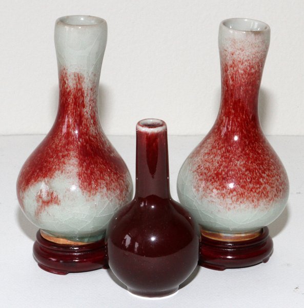 CHINESE OX BLOOD VASES THREE: CHINESE OX BLOOD VASES, THREE, H 4"-5":Including a pair with wood stands, and a single vase, stamped in blue at underside.