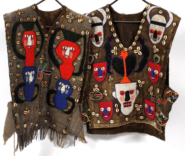 AFRICAN YORUBA BEADED VESTS TWO-: AFRICAN YORUBA BEADED VESTS, TWO, W 17"-19" L 24"-26":Both decorated in beaded mask and figure motif, with cowry shell detailing. Measuring L. 24" x 19" and H. 26" x 17" approximately.