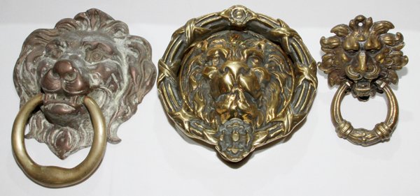 BRASS PLATED LION'S MASK DOOR KNOCKERS& PLAQUE: BRASS PLATED METAL LION'S MASK DOOR KNOCKERS (2) & PLAQUE, H 6"-11" OVERALL:Two lion head door knockers plus on lion head plaque. Three items total. From the Estate of Anne Harnett, Grosse Pointe Park