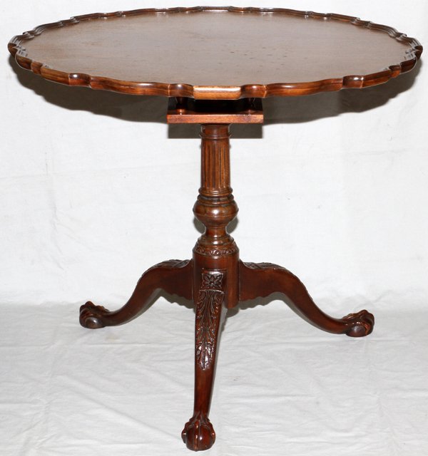 BAKER MAHOGANY TILT TOP TABLE C. 1940: BAKER, MAHOGANY TILT TOP TABLE, C. 1940, H 29", DIA 33":having a pie crest style round top with turned and fluted pedestal and tripod contoured and carved legs with ball and claw feet.