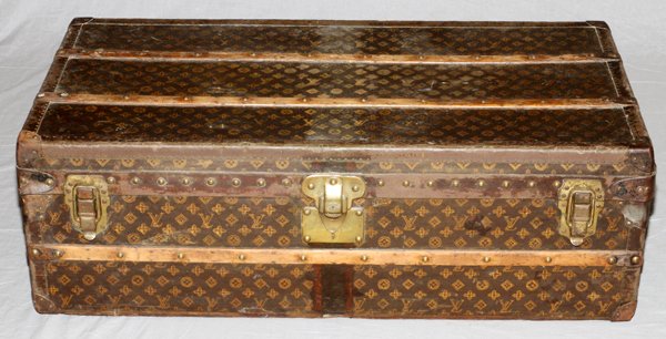 LOUIS VUITTON VINTAGE MONOGRAM CANVAS TRUNK C. 1920: LOUIS VUITTON VINTAGE MONOGRAM CANVAS TRUNK, C. 1920, H 13", L 40", D 21":Rectangular with brown monogram canvas exterior and wood banding, the hinged lid opens to linen interior and the original labe