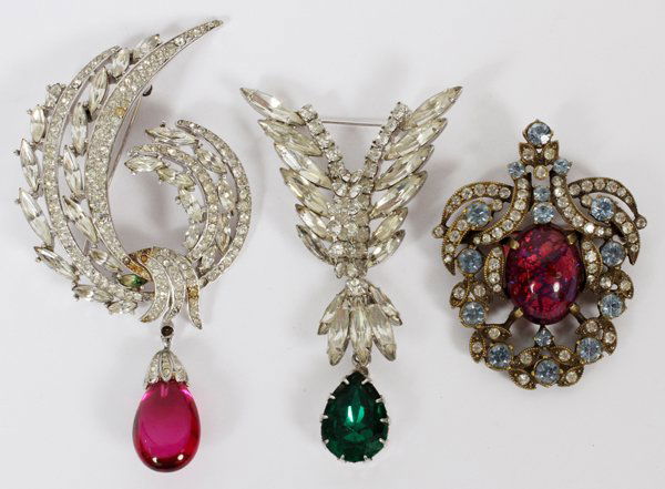 EISENBERG TRIFARI & OTHER COSTUME BROOCHES THREE: EISENBERG, TRIFARI & OTHER COSTUME BROOCHES, THREE, L 2"-3":Including 1 Eisenberg shield-form brooch with fuchsia stone at the center, signed; 1 Trifari brooch, swirl-form with fuchsia drop, signed; a