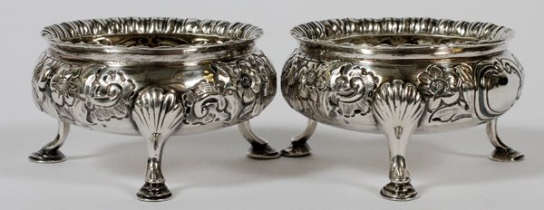 GEORGE III STERLING OPEN SALTS LONDON C. 1755 TWO: GEORGE III STERLING OPEN SALTS, LONDON, C. 1755, TWO, DIA 2 1/2":Each round sterling silver open salt has repousse scroll and foliate motifs about, on three legs; partially rubbed hallmarks include a 