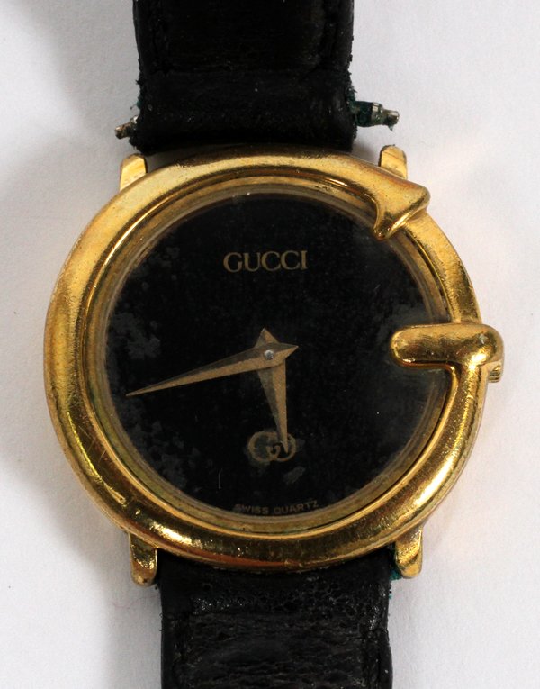 GUCCI LADY'S WRISTWATCH: GUCCI LADY'S WRISTWATCH:Swiss quartz movement, with a black dial. Case is base metal with a leather strap band. #14 6600 184. From the Estate of Anne Harnett, Grosse Pointe Park, Mi.