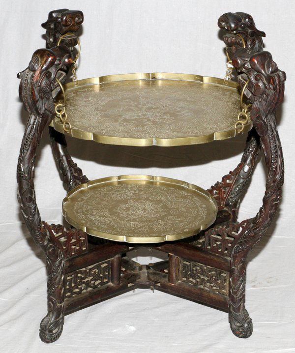 CHINESE TWO TIER DRAGON STYLE TABLE HAND CARVED: CHINESE TWO TIER, DRAGON STYLE TABLE, HAND CARVED MAHOGANY AND BRASS 19TH CENTURY H 29", W 24",:Having dragon head frame and legs to which a 22" Dia brass etched tray attaches with rings to the mouths