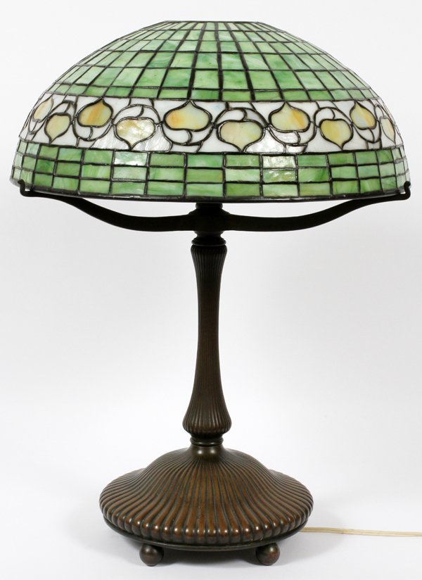 IN THE MANNER OF TIFFANY STUDIOS GLASS LAMP: IN THE MANNER OF TIFFANY STUDIOS BRONZE AND LEADED GLASS LAMP H 21.5", DIA 16":The three-light table lamp base bears the mark Tiffany Studios New York 27420 and is accompanied by a shade in the lemon 