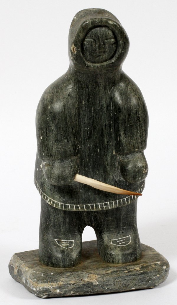 CARVED SOAPSTONE ESKIMO HUNTER: CARVED SOAPSTONE ESKIMO HUNTER, H 8 1/2":depicting a male Eskimo hunter figure dressed in winter clothing and holding a small knife made of bone.