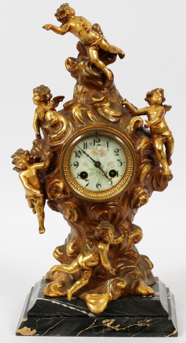 FRENCH GILT BRONZE & MARBLE MANTEL CLOCK: FRENCH GILT BRONZE & MARBLE MANTEL CLOCK, H 17", W 8":Gilt bronze swirled cloud form case with cherub figures about, having a 2 key wind with Arabic numerals at the porcelain face. Mounted to a black 