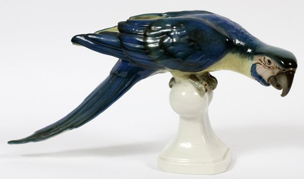 ROYAL DUX PORCELAIN FIGURE OF A PARROT EARLY 20THC: ROYAL DUX PORCELAIN FIGURE OF A PARROT, EARLY 20TH C., H 8", L 16":Including a perched parrot figure, stamped at the underside in green. Measuring H. 8" x 16", early 20th Century.