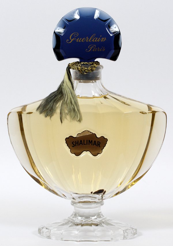 GUERLAIN OF PARIS MOLDED GLASS PERFUME FACTICE: GUERLAIN OF PARIS 'SHALIMAR' MOLDED GLASS PERFUME FACTICE, H 15":Having a sapphire blue glass stopper above a paneled urn-form bottle. Measures H.15 1/4" x 10 1/2".