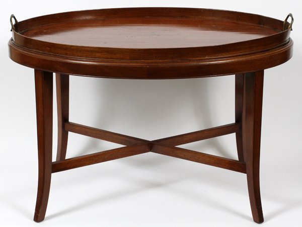 ENGLISH MAHOGANY BUTLER'S TABLE 19TH C.: ENGLISH MAHOGANY BUTLER'S TABLE, 19TH C., H 20'' W 22'' L 30'':An oval form butler’s table, fitted with a removable tray top, flanked by brass handles at either side. Joined by an X-form stretcher a