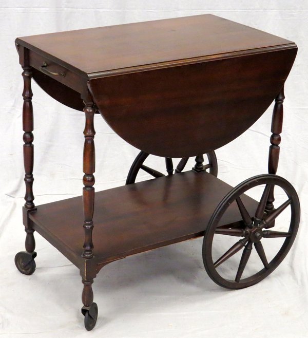 MAHOGANY TEA CART W/ DROP LEAF: MAHOGANY TEA CART WITH DROP LEAF, H 28", L 25":Mahogany tea cart with large spoke rear wheels and small swiveling front wheels, two rounded drop leaves and spindle corner frames and lower shelf. Measu
