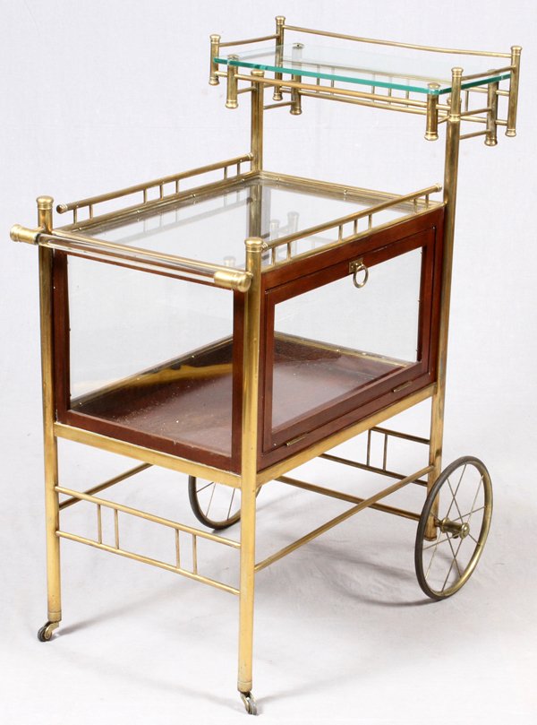 CONTINENTAL BRASS & GLASS SERVING CART 20TH C.: CONTINENTAL BRASS & GLASS SERVING CART, EARLY 20TH C., H 39", L 32":Raised on large wheels and casters at the front and back, fitted with an upper glass shelf. Measuring H.39" x 32" x 17", early 20th 