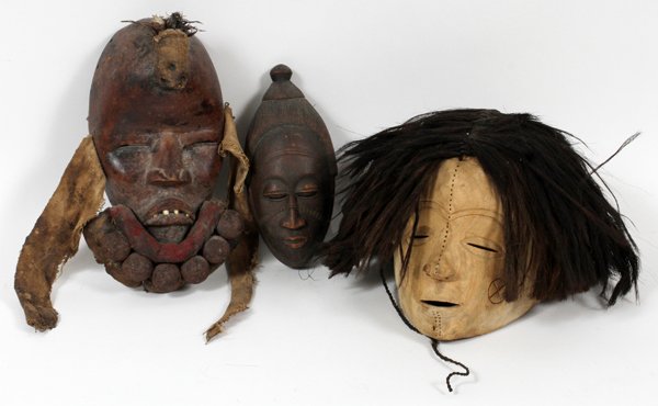 AFRICAN CARVED TRIBAL MASKS THREE: AFRICAN CARVED TRIBAL MASKS, THREE, L 8" & 11":Including one ovoid form mask, adorned with scarification to the cheeks, L. 8"; together with one ovoid form mask, with applied stuffed cloth balls about
