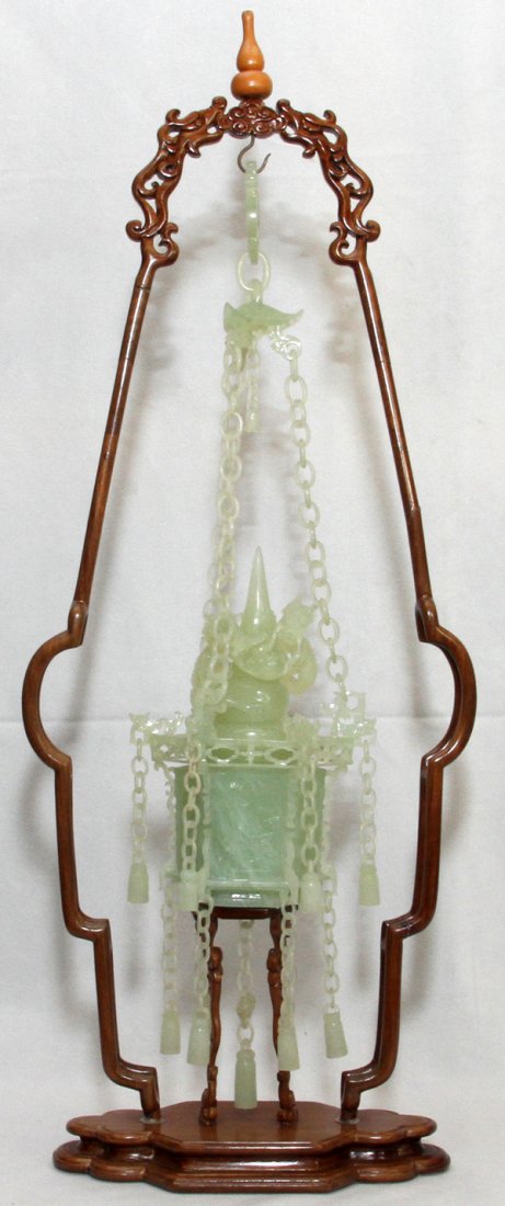 CHINESE CARVED JADE LANTERN W/IN A WOOD FRAME: CHINESE CARVED JADE LANTERN WITHIN A WOOD FRAME, H 25", W 9 1/2" OVERALL:Light green jade carved as a hexagonal lantern hung from jade rings, with two dragons at the top, suspended within a wooden fra