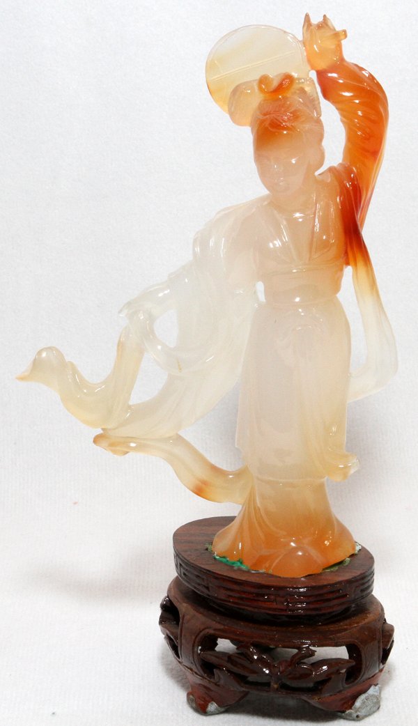 CHINESE CARVED CARNELIAN FIGURE: CHINESE CARVED CARNELIAN FIGURE, H 4 3/4":Creamy white with rust accents, carved as a standing beauty with fan. Mounted on a wood base.