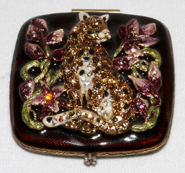 JAY STRONGWATER ENAMELED & JEWELED COMPACT: JAY STRONGWATER ENAMELED & JEWELED COMPACT, W 2 3/4":Decorated with a center leopard, seated amongst purple flowers. Opens to a mirrored interior, measuring W.2 3/4" x 2 3/4".