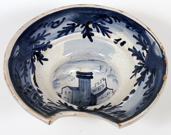 CONTINENTAL FAIENCE SHAVING BOWL LATE 19TH C.: CONTINENTAL FAIENCE SHAVING BOWL, LATE 19TH C., H 4", W 11 3/4":Decorated in blue with a castle in the well with a floral border.