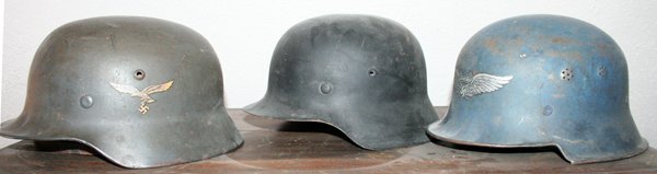 WWII GERMAN METAL MILITARY HELMETS C1940 3 PCS.: WWII GERMAN METAL MILITARY HELMETS, C1940, 3 PCS., H 6", L 10":includes one having a stencil eagle on front and inscribed "Luftschutz". One in green with tricolor painted shield on right side and Wehr
