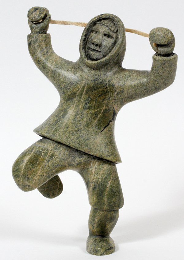 INUIT CARVED STONE STANDING FIGURE: INUIT CARVED STONE STANDING FIGURE, H 11", W 7":A male figure standing on one foot, arms overhead, holding sinew. No apparent markings. For a high resolution photo