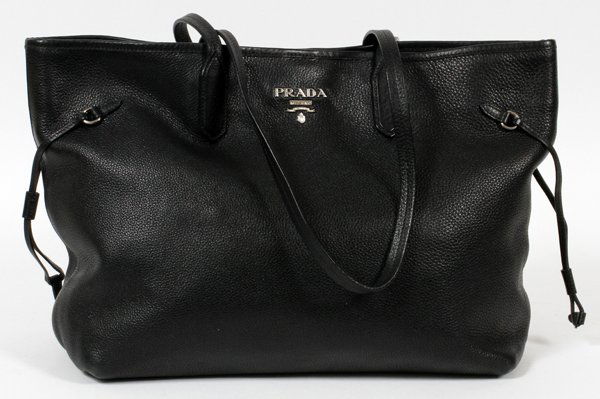 PRADA BLACK LEATHER BAG: PRADA BLACK LEATHER BAG, W 17 1/2":Clips open to a fabric lined interior, with a single zippered pocket; labeled: Prada, Milano at the exterior and interior. Measuring H. 11" x 17 1/2", L. 12" to the
